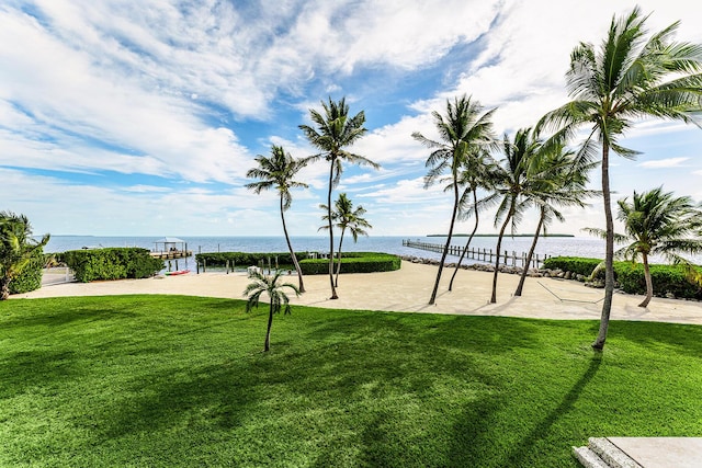 view of home's community with a water view, volleyball court, and a lawn