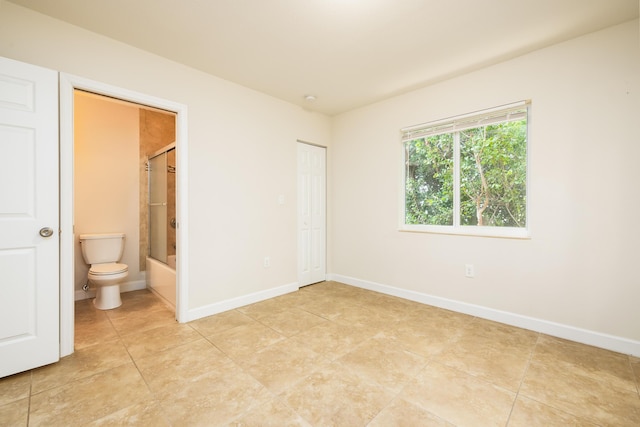 unfurnished bedroom with ensuite bath and light tile patterned floors