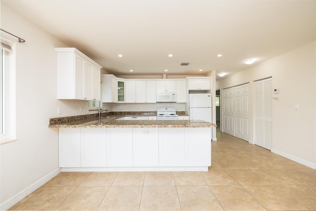 kitchen with sink, dark stone countertops, white cabinets, kitchen peninsula, and white appliances