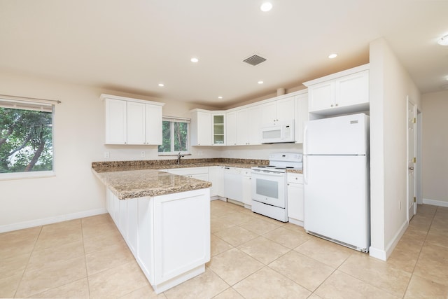 kitchen with sink, white cabinetry, dark stone countertops, kitchen peninsula, and white appliances