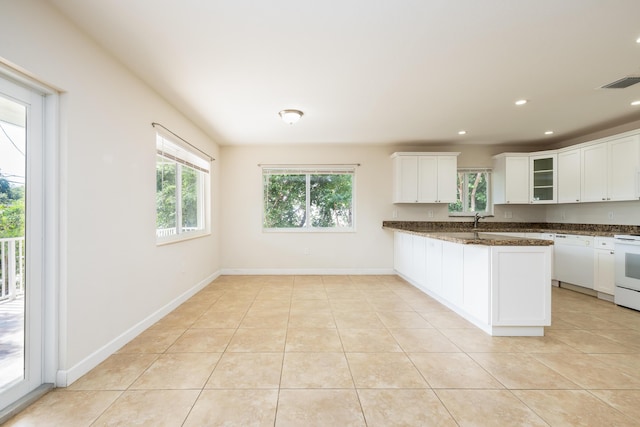 kitchen with white cabinetry, light tile patterned flooring, dark stone countertops, and kitchen peninsula