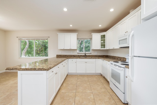 kitchen with white cabinetry, sink, white appliances, and dark stone counters