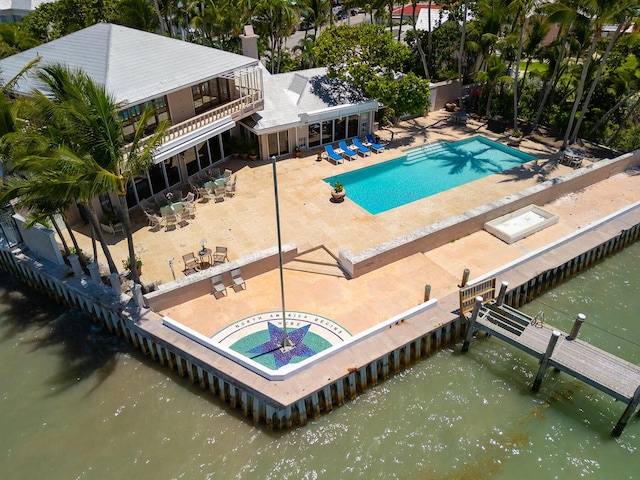 community pool with a water view, a patio area, and a boat dock