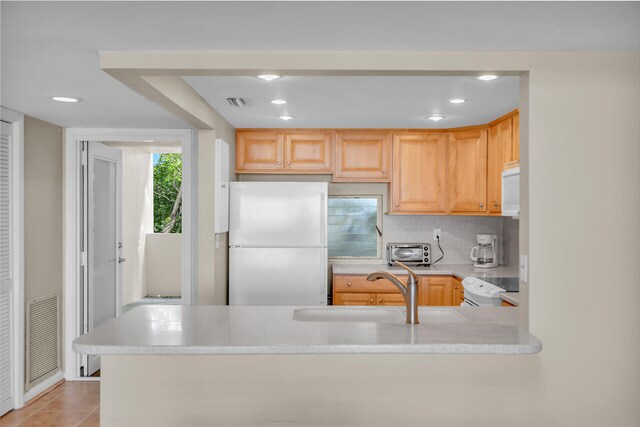 kitchen featuring sink, white appliances, kitchen peninsula, and light brown cabinets