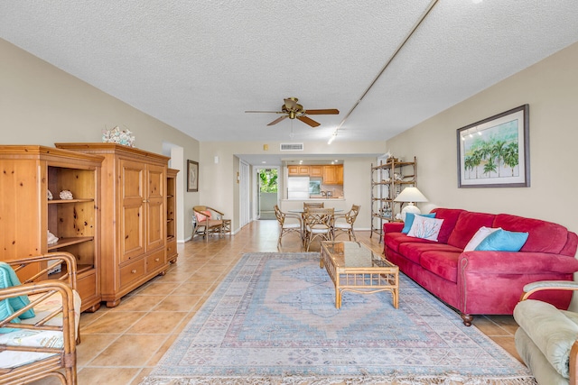 living room featuring ceiling fan, light tile patterned floors, and a textured ceiling