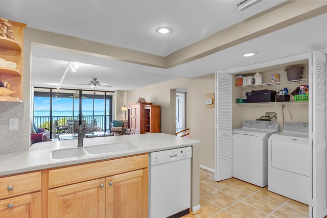 kitchen with sink, light tile patterned floors, independent washer and dryer, white dishwasher, and light brown cabinets