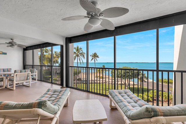 sunroom / solarium with a water view, ceiling fan, and a wealth of natural light