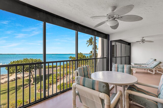 sunroom / solarium with ceiling fan and a water view