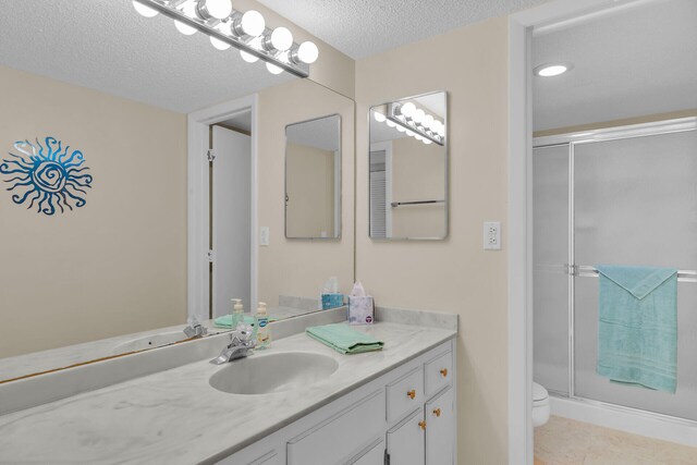 bathroom with a shower with shower door, tile patterned flooring, vanity, toilet, and a textured ceiling