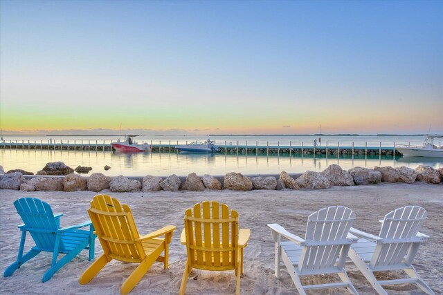 patio terrace at dusk featuring a beach view and a water view