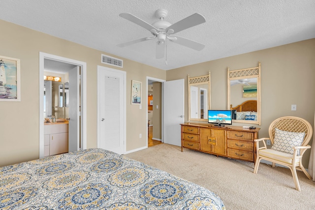 carpeted bedroom featuring sink, ensuite bath, a textured ceiling, and ceiling fan