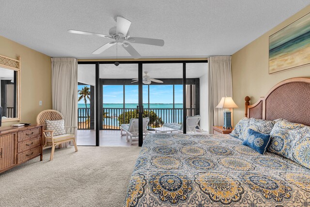 carpeted bedroom with a water view, a wall of windows, access to exterior, and a textured ceiling