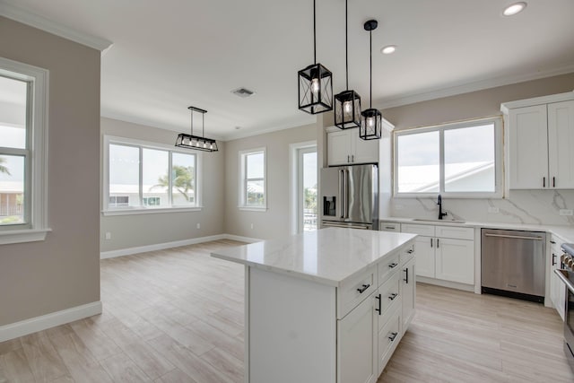 23066 Tarpon Ln, Cudjoe, FL 33042 - kitchen with stainless steel appliances, a sink, crown molding, a center island, and light stone countertops