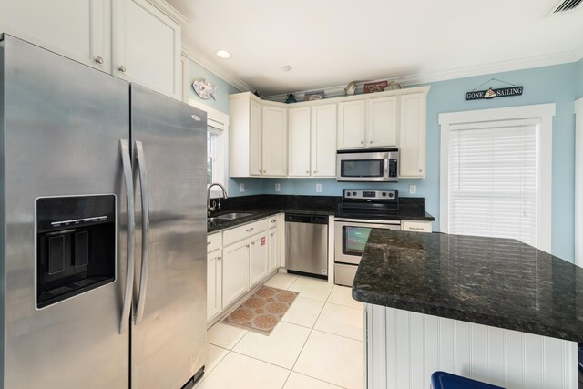 kitchen featuring sink, light tile patterned floors, ornamental molding, appliances with stainless steel finishes, and dark stone counters