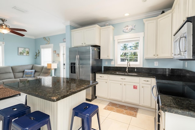 kitchen featuring sink, a kitchen breakfast bar, ornamental molding, light tile patterned floors, and stainless steel appliances