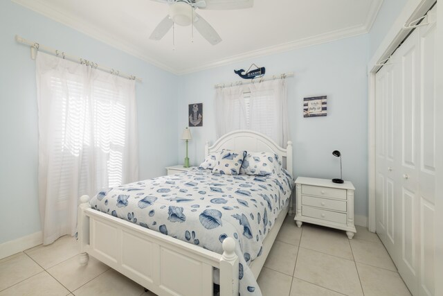 tiled bedroom featuring ornamental molding, ceiling fan, and a closet