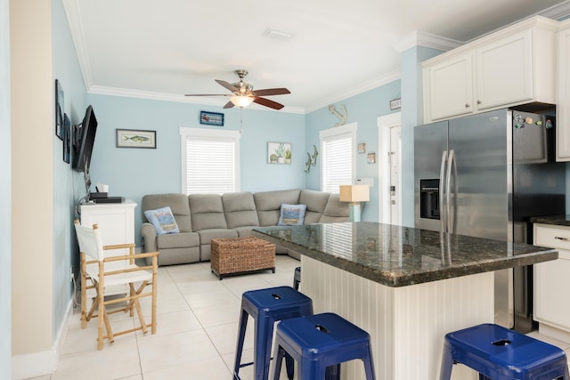 kitchen featuring light tile patterned flooring, a breakfast bar area, stainless steel fridge with ice dispenser, ornamental molding, and white cabinets