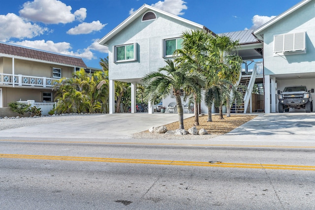918 W Ocean Dr, Key Colony, FL 33051 - view of front of house featuring a carport, stairs, concrete driveway, metal roof, and an AC wall unit