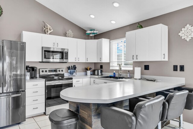 918 W Ocean Dr, Key Colony, FL 33051 - kitchen with stainless steel appliances, a sink, a peninsula, a kitchen bar, and lofted ceiling