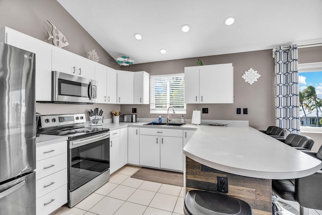 918 W Ocean Dr, Key Colony, FL 33051 - kitchen with stainless steel appliances, a sink, a peninsula, a breakfast bar, and light countertops