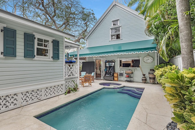 rear view of property featuring a pool with hot tub and a patio area