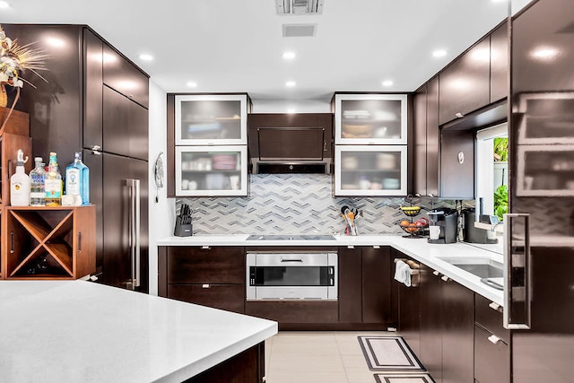 kitchen featuring black electric cooktop, tasteful backsplash, dark brown cabinetry, and oven