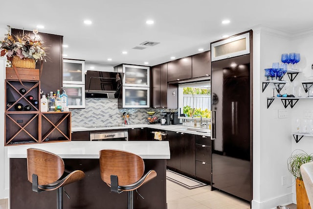 kitchen with sink, a breakfast bar area, tasteful backsplash, ventilation hood, and oven