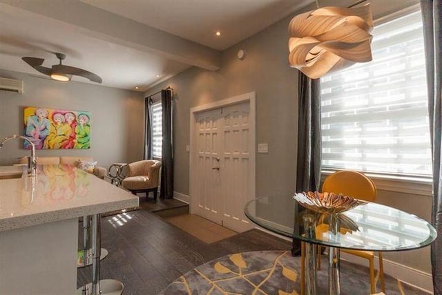 dining space with sink, hardwood / wood-style flooring, ceiling fan, a wall mounted air conditioner, and beamed ceiling