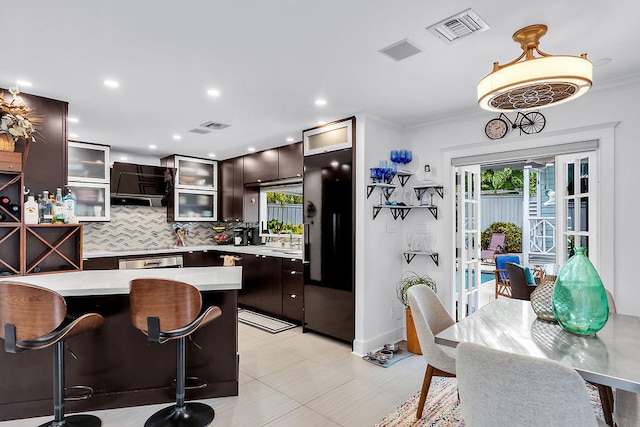 kitchen featuring tasteful backsplash, pendant lighting, dark brown cabinets, and fridge