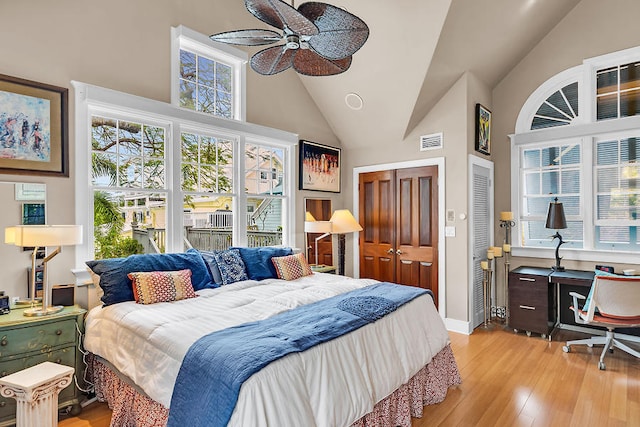 bedroom featuring multiple closets, ceiling fan, high vaulted ceiling, and light hardwood / wood-style flooring