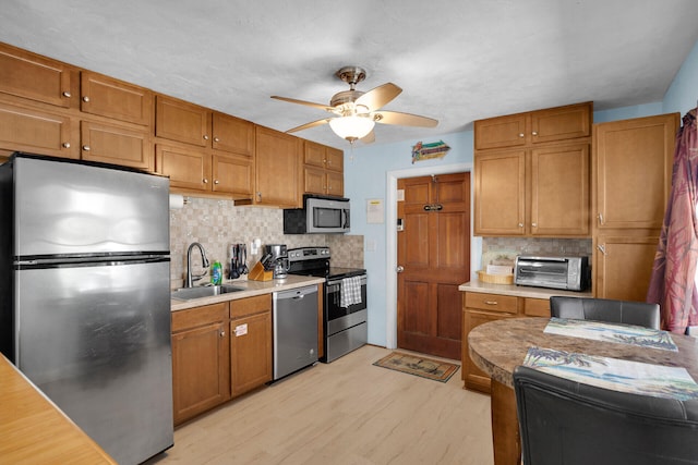 kitchen with tasteful backsplash, appliances with stainless steel finishes, sink, and light hardwood / wood-style flooring