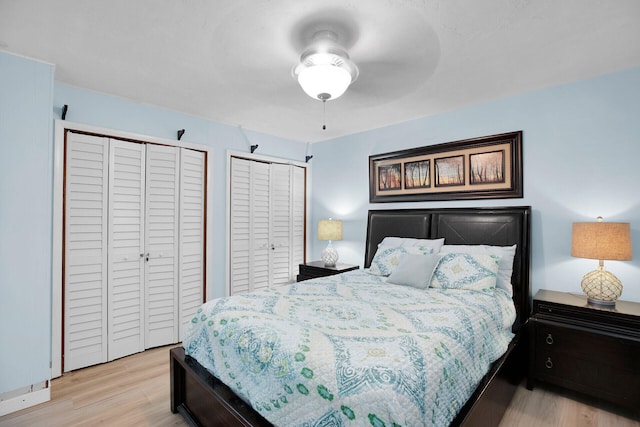 bedroom with light hardwood / wood-style flooring and two closets