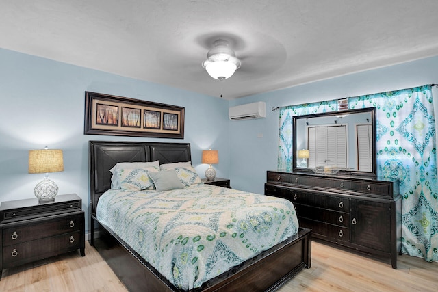 bedroom featuring light hardwood / wood-style flooring, a wall unit AC, and ceiling fan