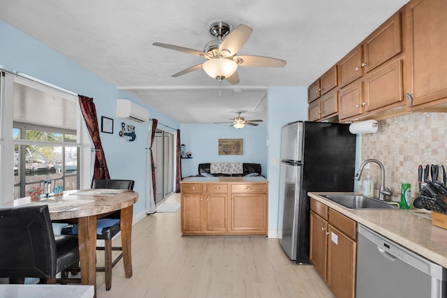 kitchen with sink, light hardwood / wood-style flooring, appliances with stainless steel finishes, a wall unit AC, and decorative backsplash