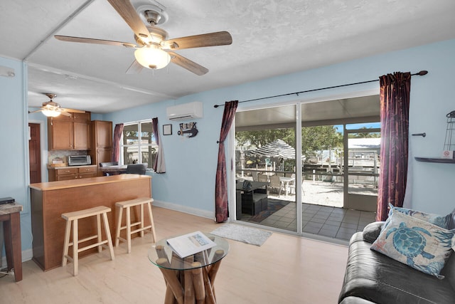 living room featuring a wall mounted air conditioner, a textured ceiling, a healthy amount of sunlight, and ceiling fan