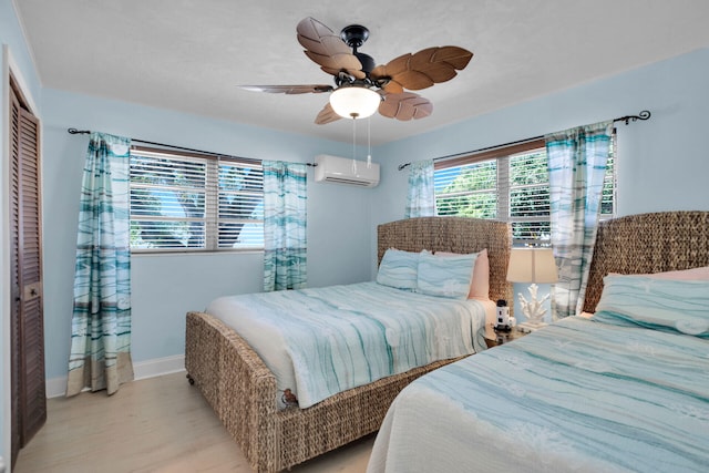 bedroom with ceiling fan, a wall mounted AC, a closet, and light wood-type flooring