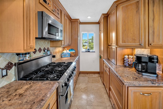 175 Galleon Rd, Islamorada, FL 33036 - kitchen featuring appliances with stainless steel finishes, tasteful backsplash, brown cabinets, stone counters, and a textured ceiling