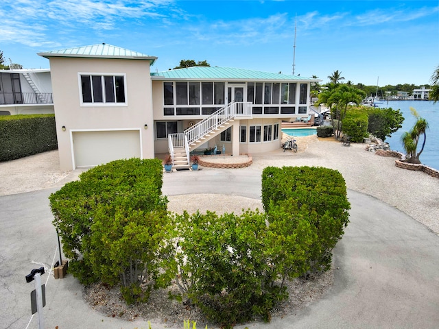 175 Galleon Rd, Islamorada, FL 33036 - back of property with a sunroom, stucco siding, an attached garage, a standing seam roof, and driveway