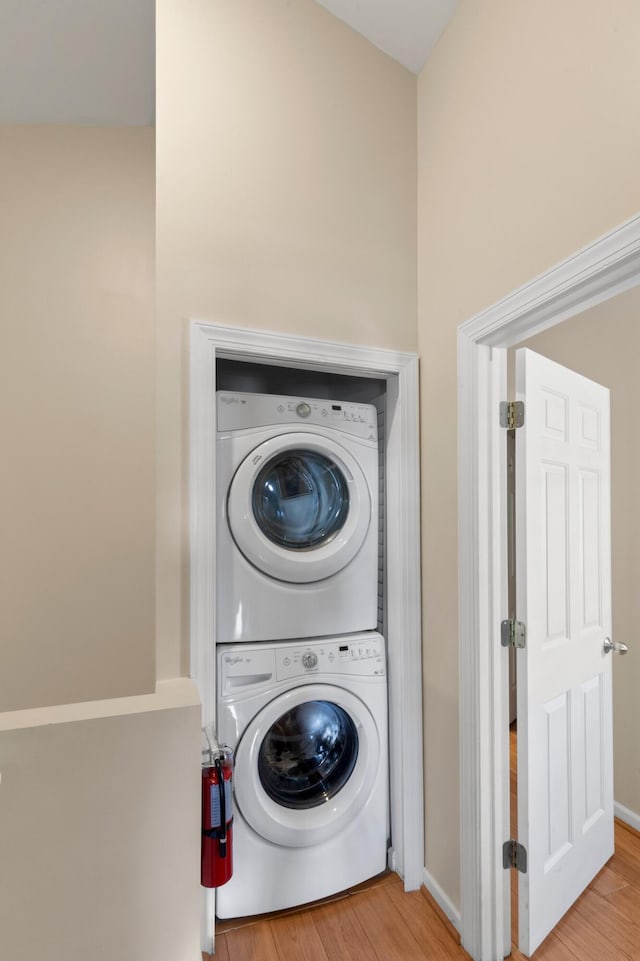 clothes washing area featuring laundry area, stacked washer / dryer, and wood finished floors