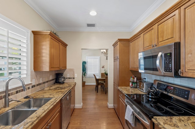 kitchen featuring a sink, visible vents, light wood-style floors, ornamental molding, and appliances with stainless steel finishes