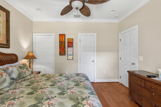 bedroom featuring visible vents, crown molding, baseboards, and wood finished floors