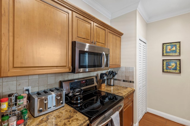 kitchen with tasteful backsplash, baseboards, appliances with stainless steel finishes, ornamental molding, and wood finished floors