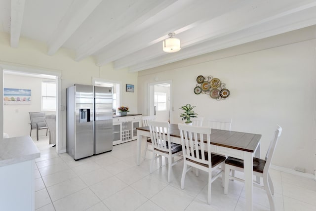 dining space with plenty of natural light, light tile patterned floors, and beam ceiling