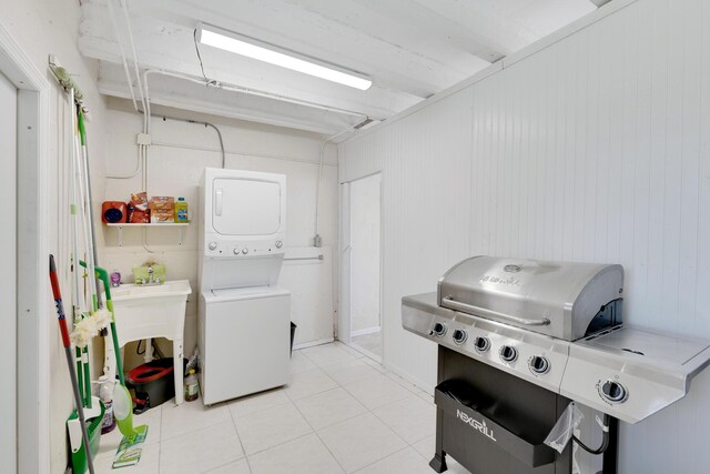 laundry area featuring light tile patterned floors and stacked washer / dryer