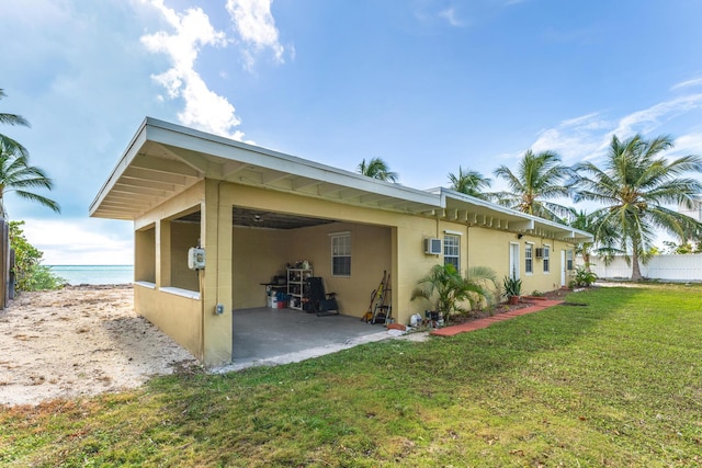 back of house featuring a water view, a carport, and a yard