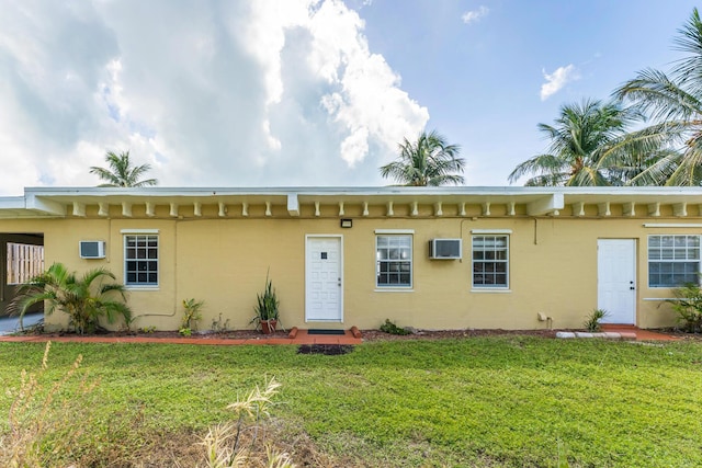 view of front of property featuring a wall mounted air conditioner and a front lawn