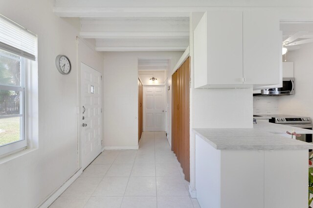 kitchen featuring beamed ceiling, light tile patterned floors, and white cabinets