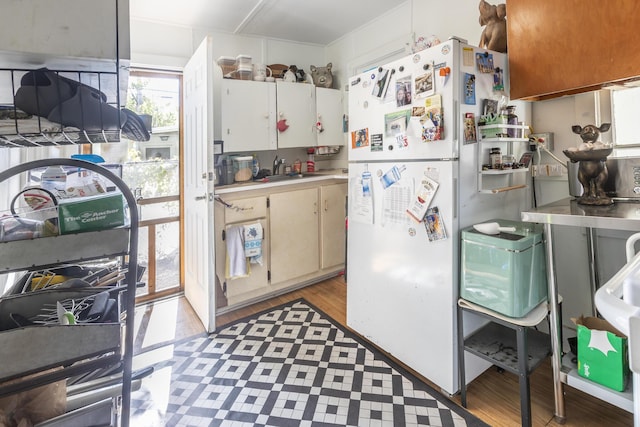 kitchen featuring white cabinetry, sink, light hardwood / wood-style floors, and white fridge