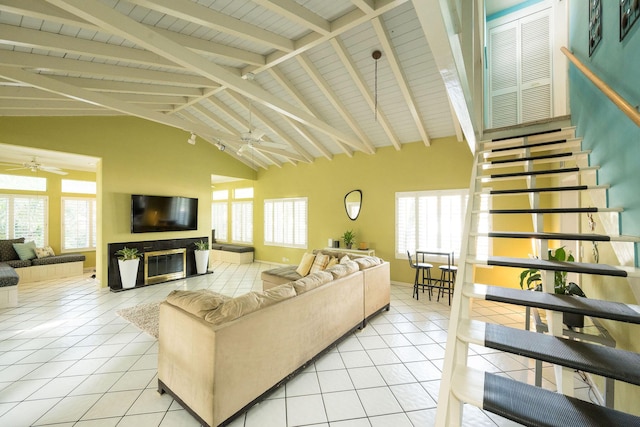 living room with light tile patterned flooring, a glass covered fireplace, and a ceiling fan