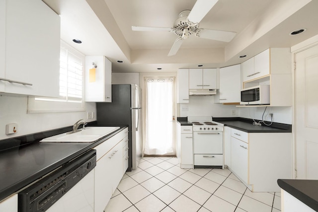 kitchen featuring dark countertops, white cabinets, a sink, white appliances, and under cabinet range hood